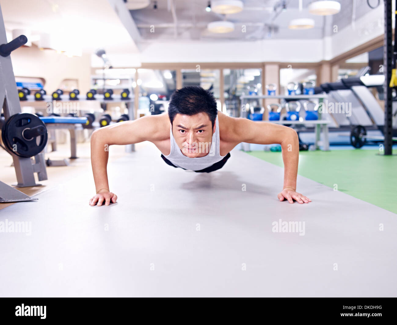 man doing push-ups on gym floor. Stock Photo