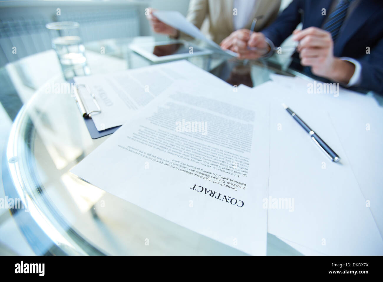 Business documents and pen at workplace with working people on ...