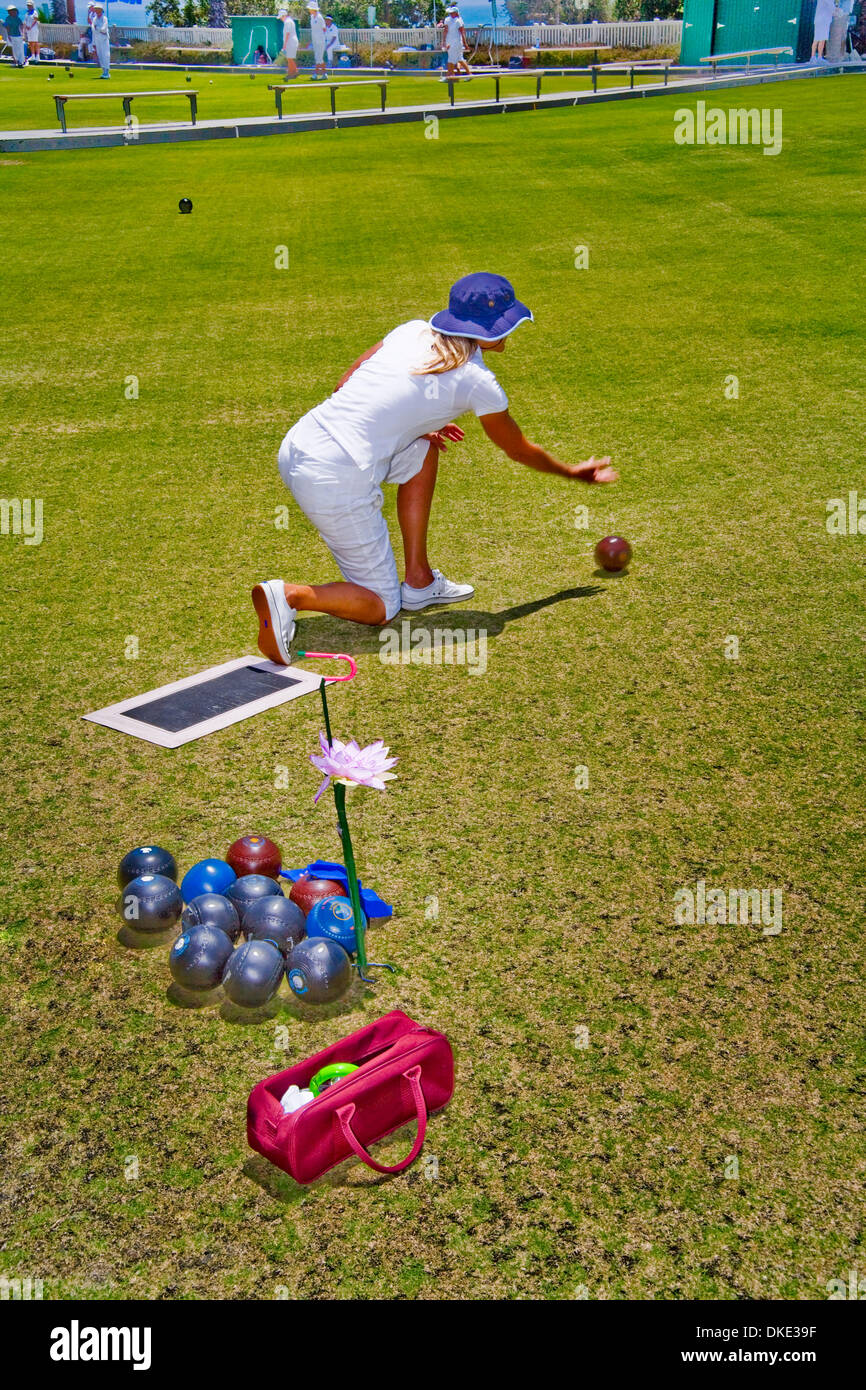 Jul 30, 2007 - Laguna Beach, CA, USA - Wearing the regulation white uniform,  a young woman hefts a 'bowl' (ball) during a lawn bowling competition on a bowling green in Laguna Beach, CA . The object of the game is to roll the asymmetrical balls as close as as possible to a previously-rolled white 'jack' without actually touching it. Note the orchid decorating her bowls holder (for Stock Photo