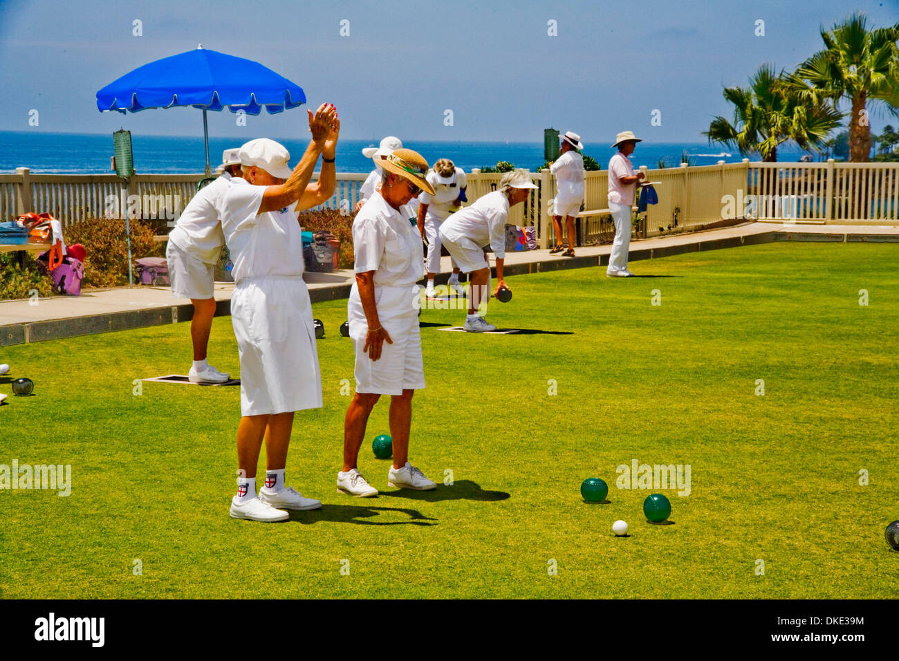 Jul 30, 2007 - Laguna Beach, CA, USA - Wearing the regulation white uniform, a woman player applauds a close roll of the asymmetrical 'bowl' (ball) during a lawn bowling competition on a bowling green in Laguna Beach, CA.The object of the game is to roll bowls as close to the previously-rolled white 'jack' ball as possible without touching it. (Credit Image: © Spencer Grant/ZUMA Pr Stock Photo