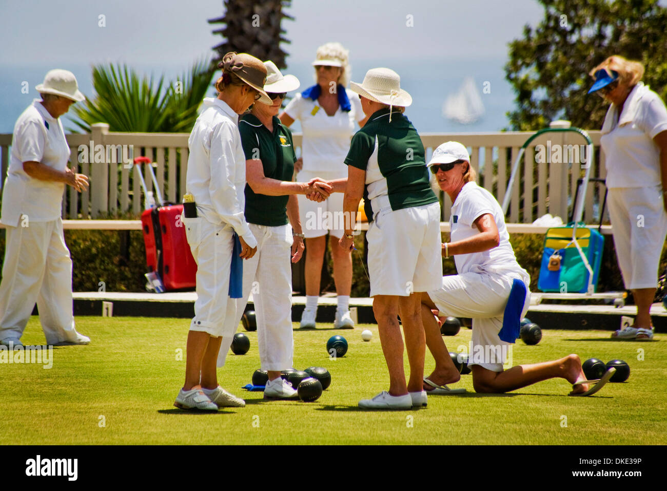 Jul 30, 2007 - Laguna Beach, CA, USA - Wearing the regulation white uniforms, one woman player congratulates a team mate on a 'good throw' during a lawn bowling competition on a bowling green in Laguna Beach, CA . The object of the game is to roll the 'bowls' (asymmetrical balls) as close as as possible to the previously-rolled white 'jack' (visible in center background) without ac Stock Photo