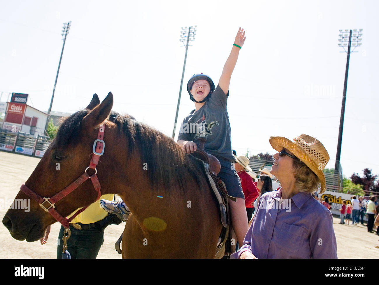 Joan Gillette, right, of Palo Cedro and a member of the Redding Rodeo Association Auxiliary, walks with Mason Roberts, 12, of Redding, waving is his arm in delight after riding a horse for the first time Monday during Special Kids Day at the Redding Rodeo Grounds. The Asphalt Cowboys and Redding Rodeo Association worked together to offer horse and carriages rides to local youth wit Stock Photo