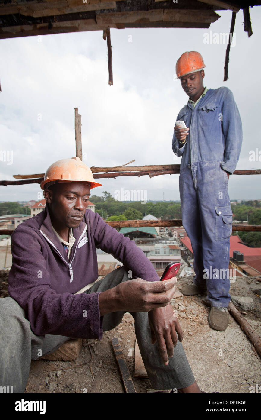 Workmen using mobile phones on construction site, Nairobi, Kenya Stock
