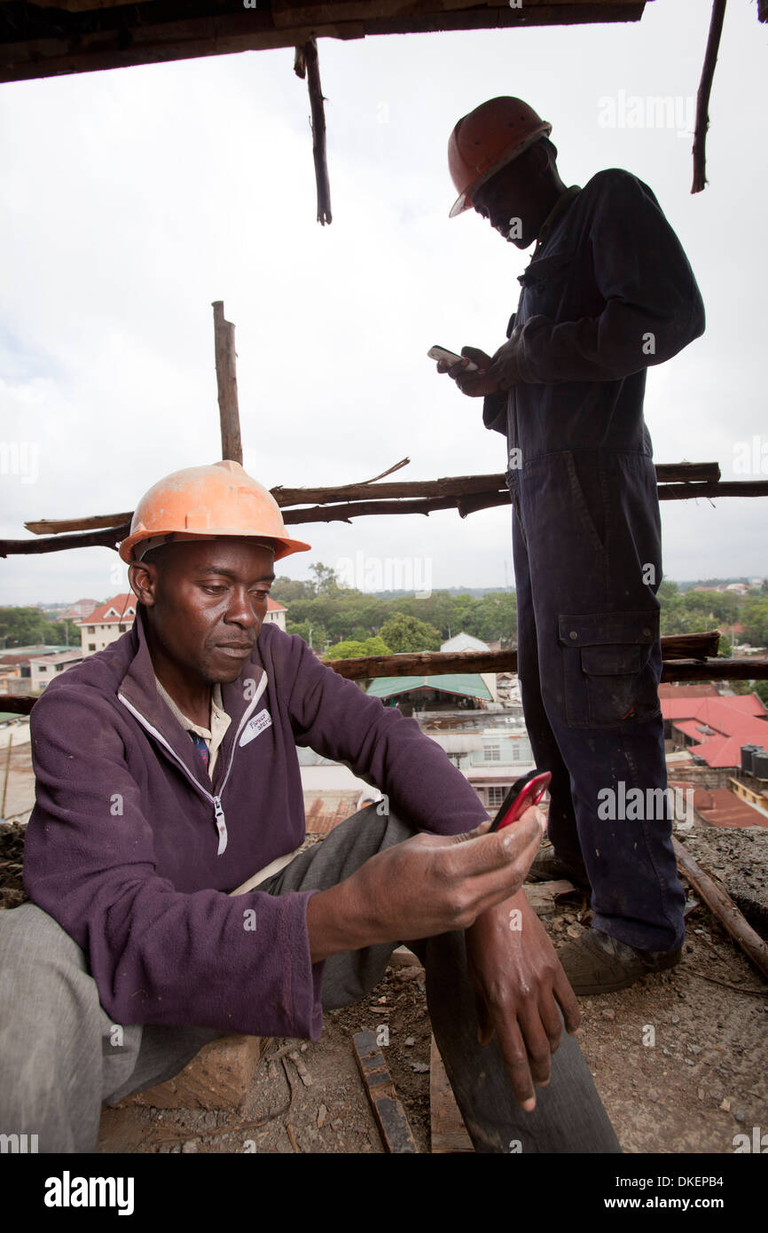 Workmen using mobile phones on construction site, Nairobi, Kenya Stock