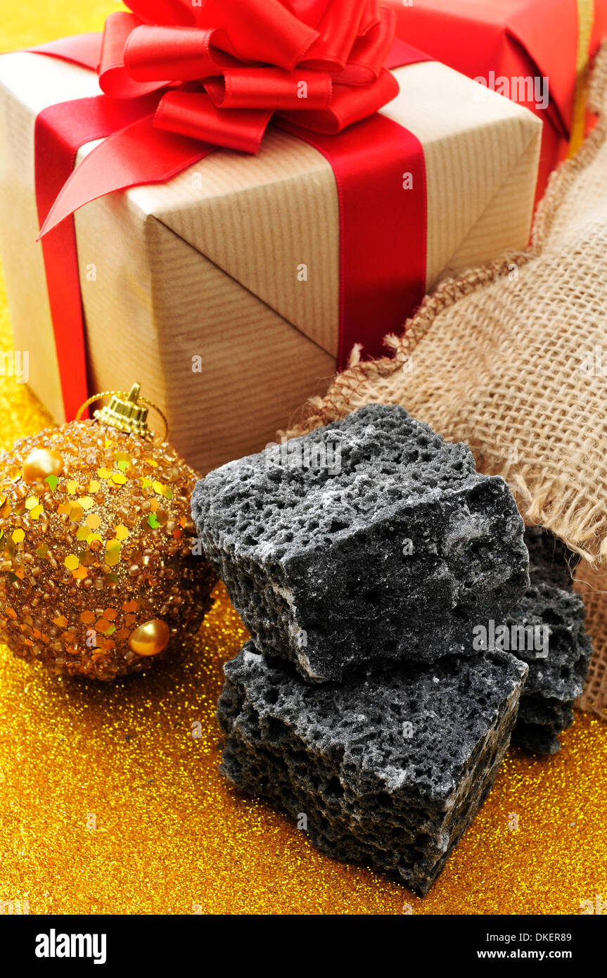 some lumps of candy coal and some christmas ornaments and gifts Stock Photo