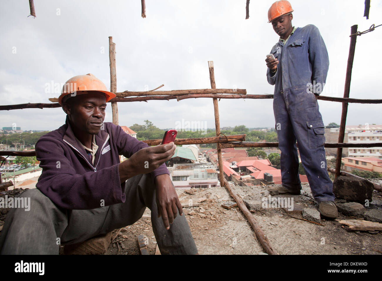Workmen using mobile phones on construction site, Nairobi, Kenya Stock