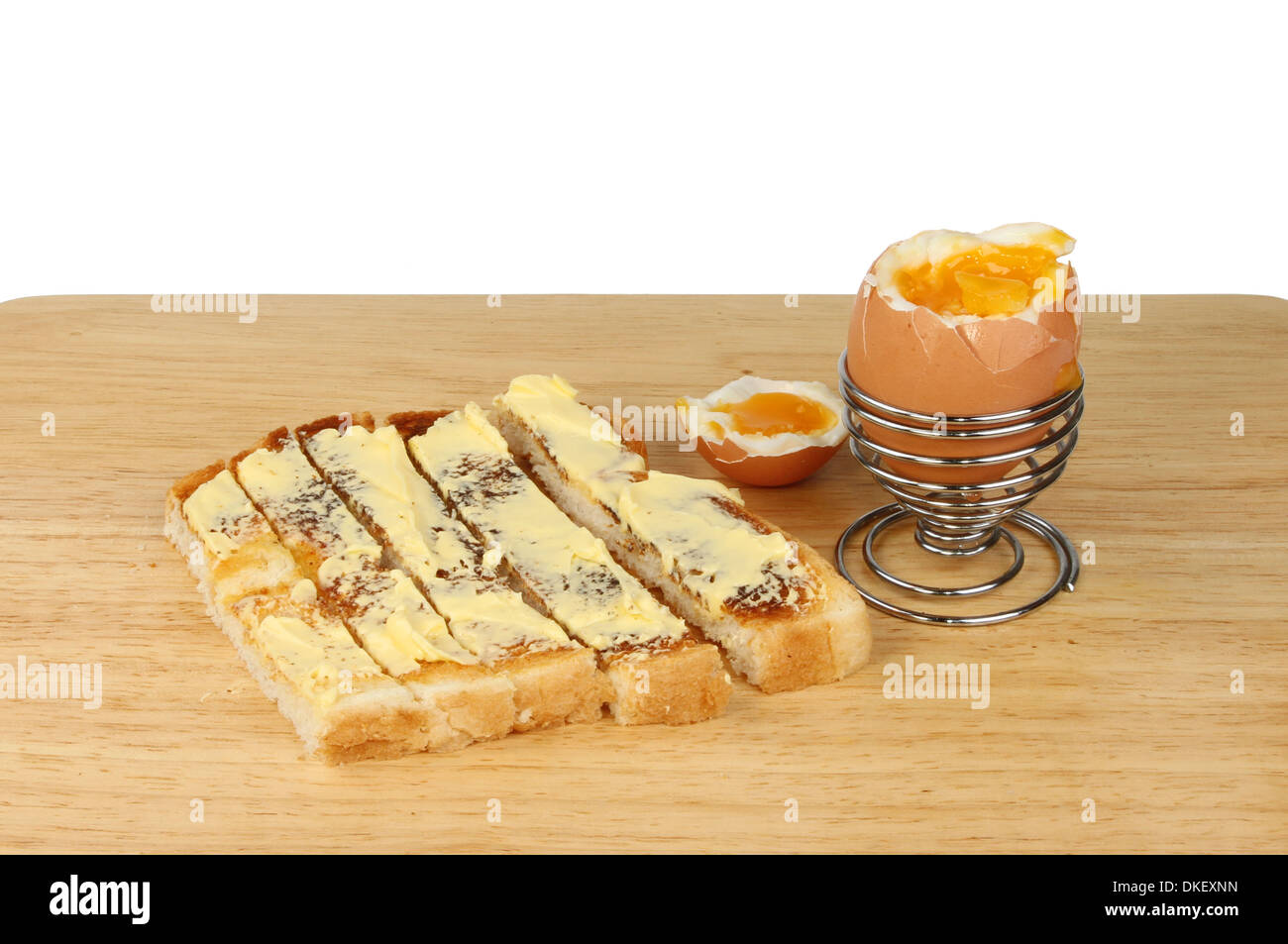 Soft boiled egg and toast soldiers on a wooden board against a white background Stock Photo