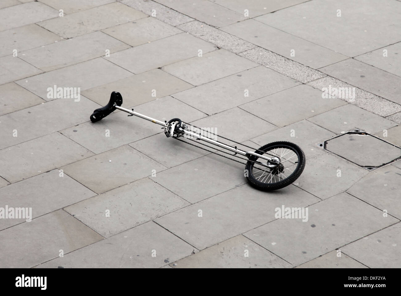 It's a photo of a monocycle or unicycle that is on the ground or floor on tiles in the street outdoor Stock Photo