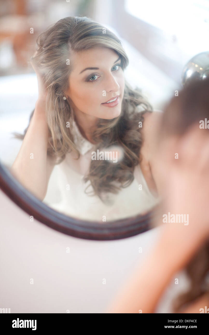 Young woman checking herself in wall mirror Stock Photo Alamy