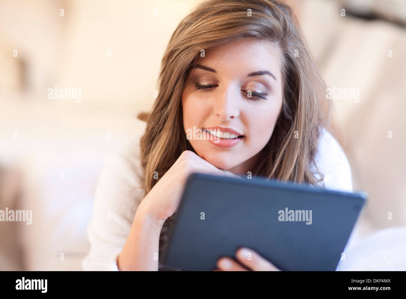 Young woman lying in bed with digital tablet Stock Photo