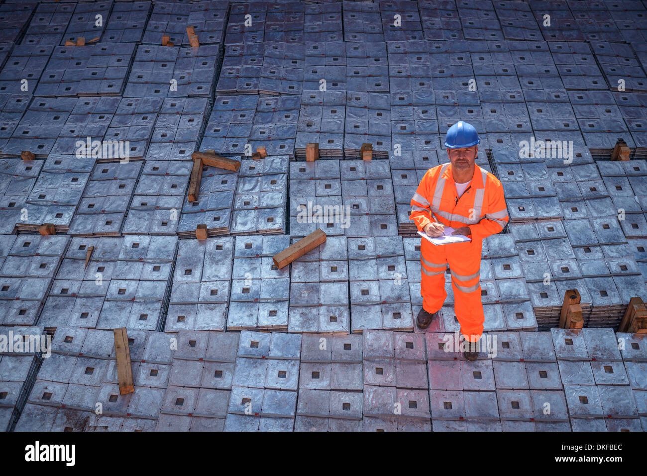 Worker in reflective workwear standing on metal alloy cargo in ship's hold, portrait Stock Photo