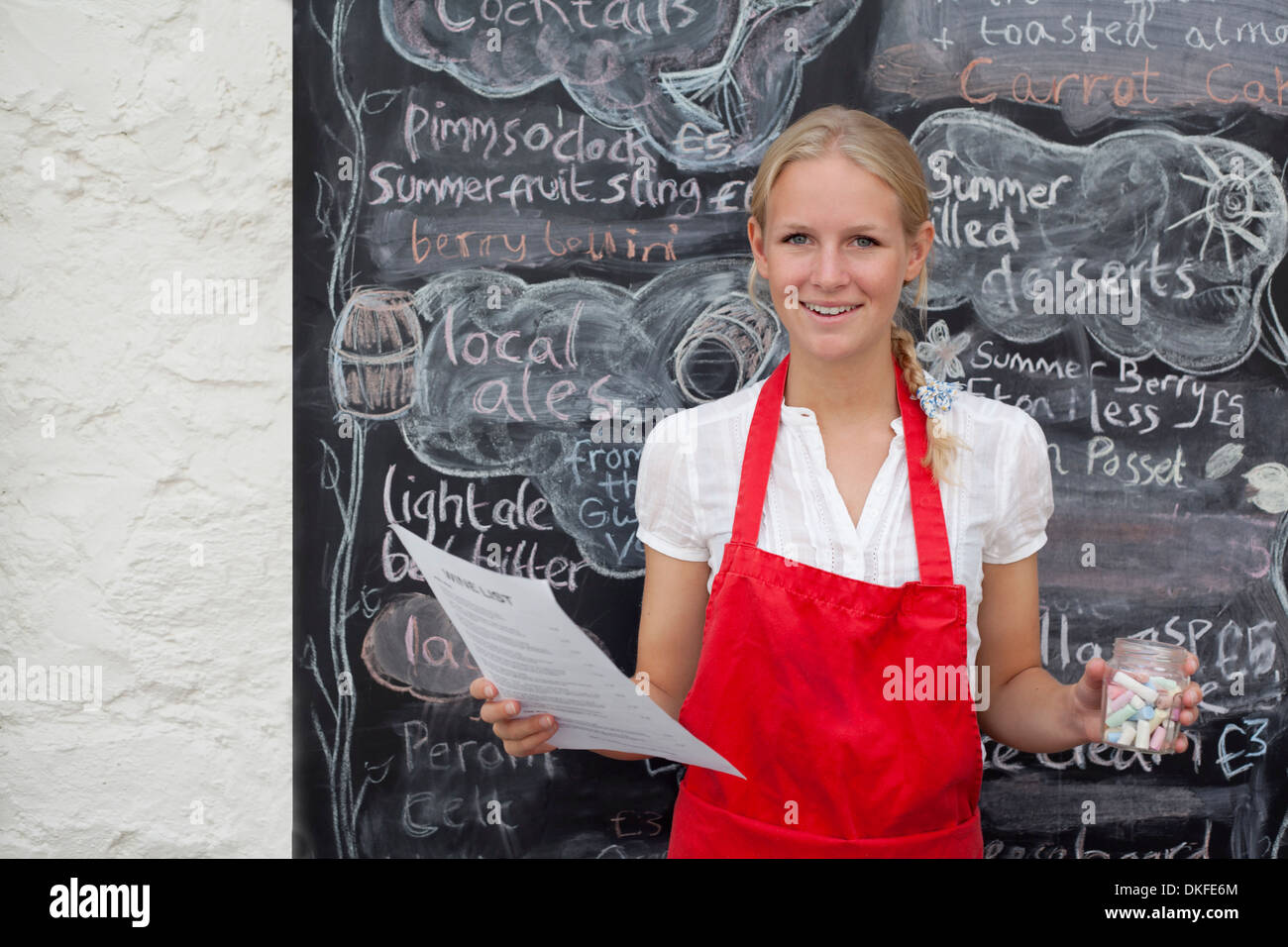 Waitress holding jar of chalk and menu in cafe Stock Photo