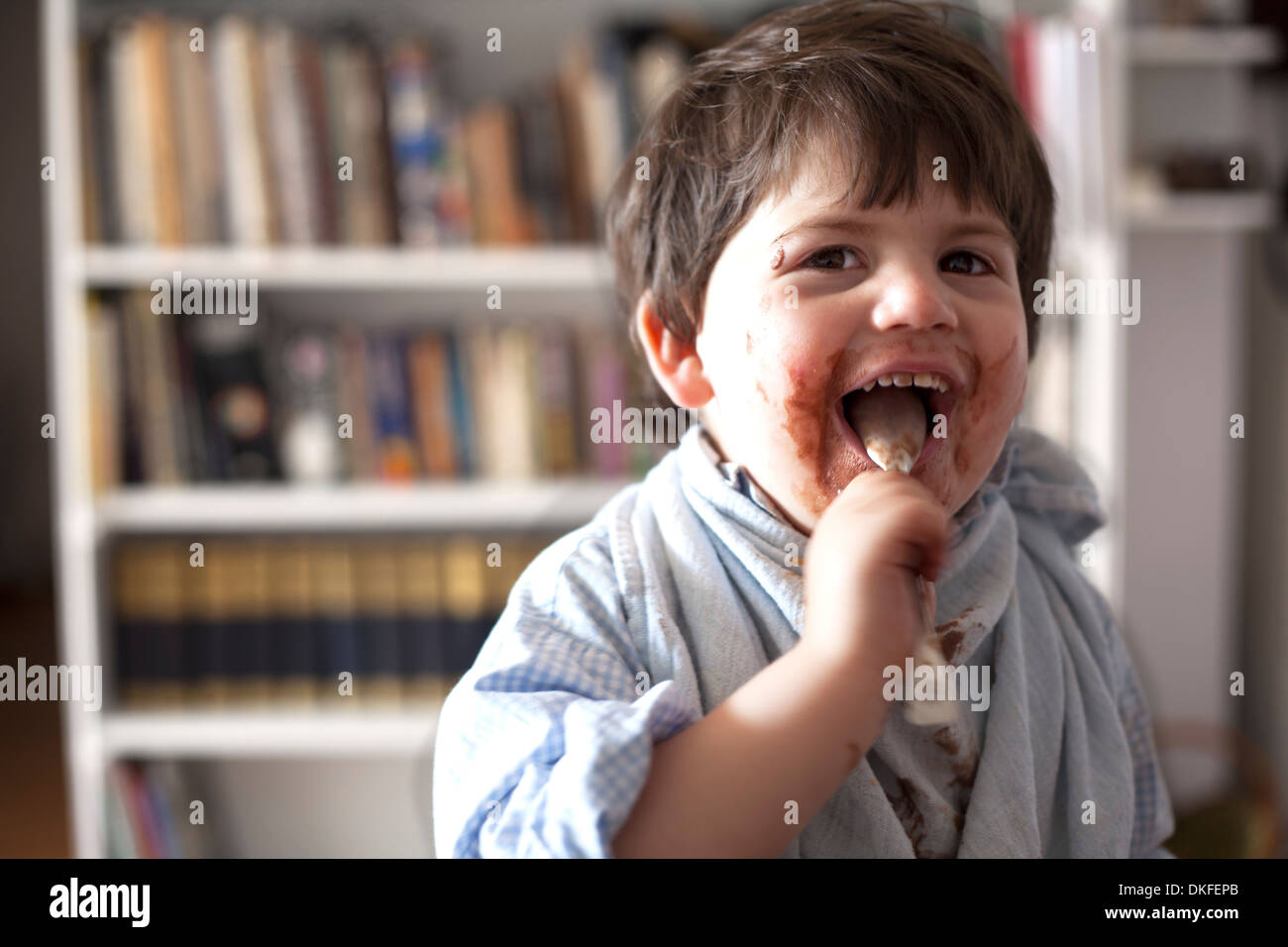 Portrait of male toddler licking chocolate covered teaspoon Stock Photo