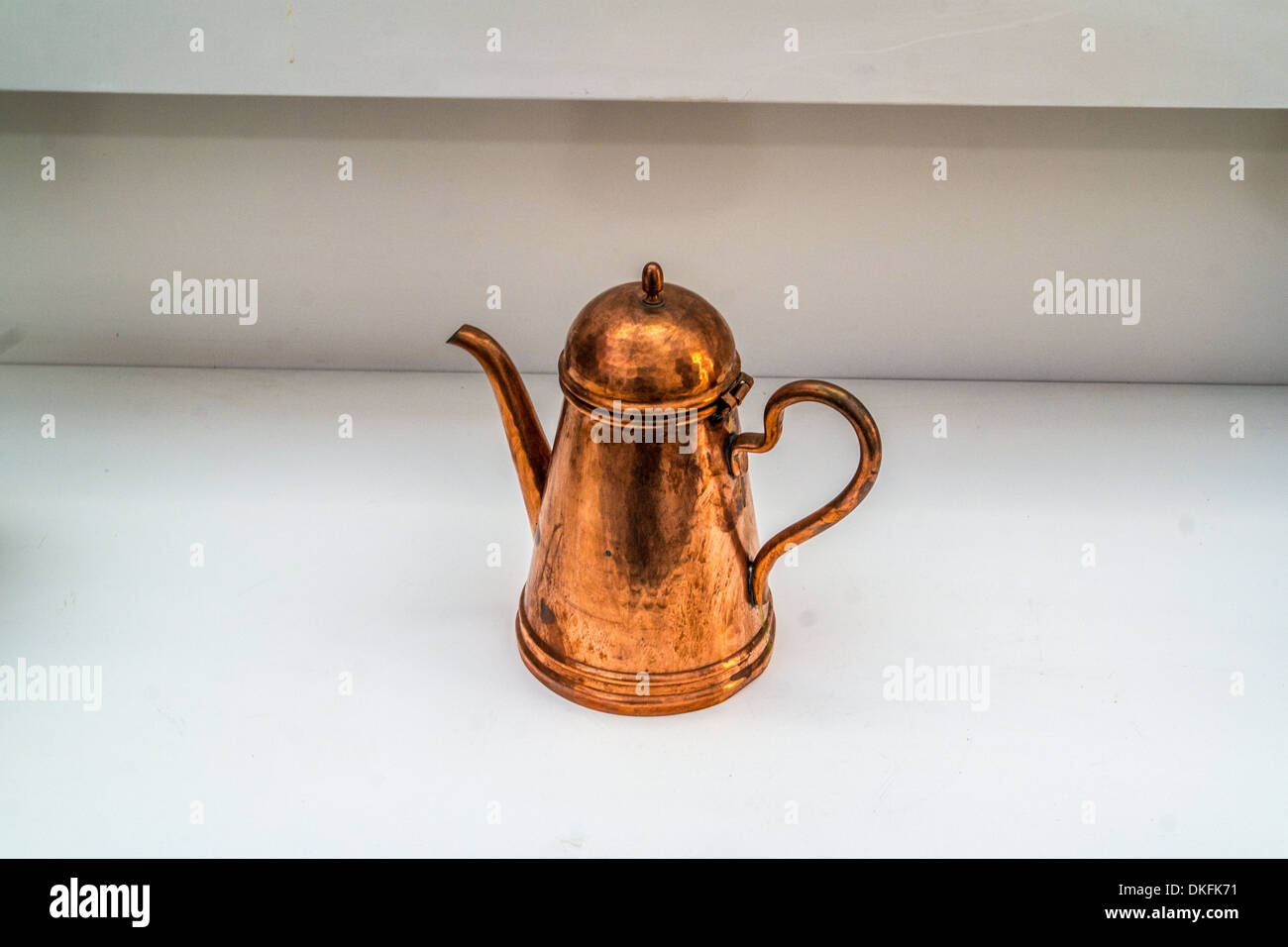 Copper jug with a handle and a pouring spout on a white background