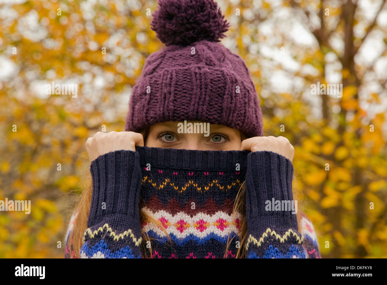 Close up portrait of young woman in park with jumper hiding face Stock Photo