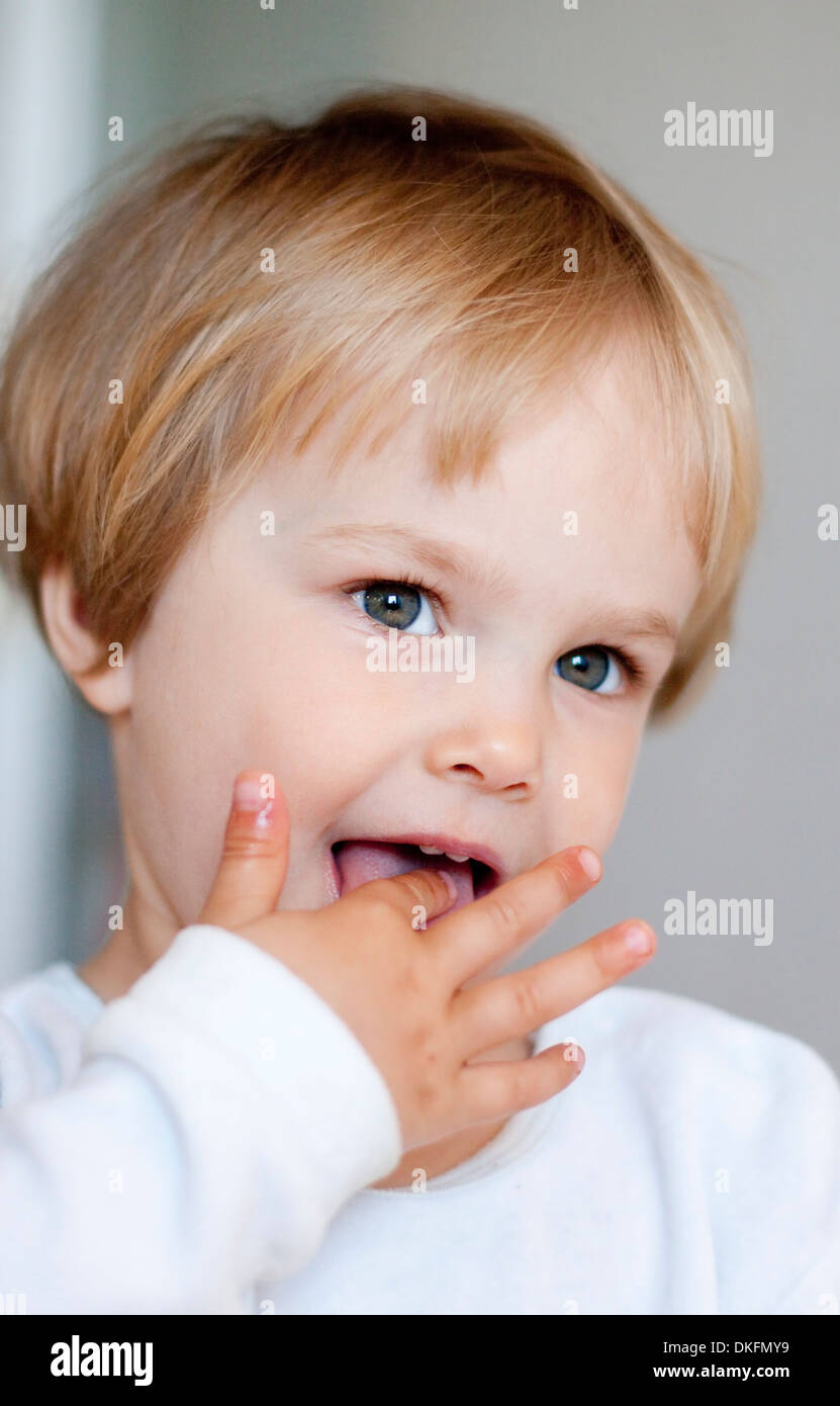 Little blond girl with finger in mouth Stock Photo