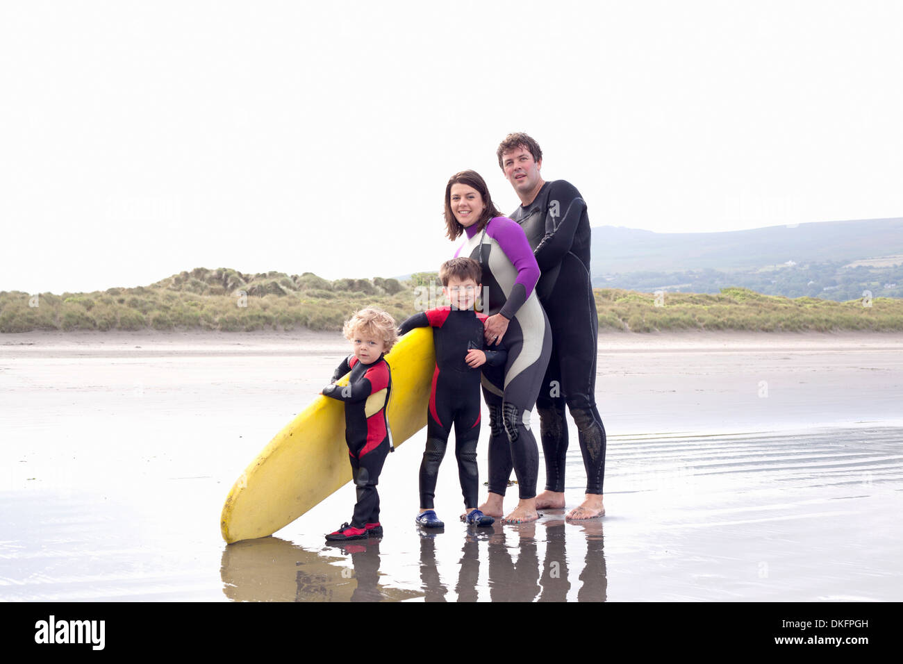 Family with two boys and surfboard on beach Stock Photo