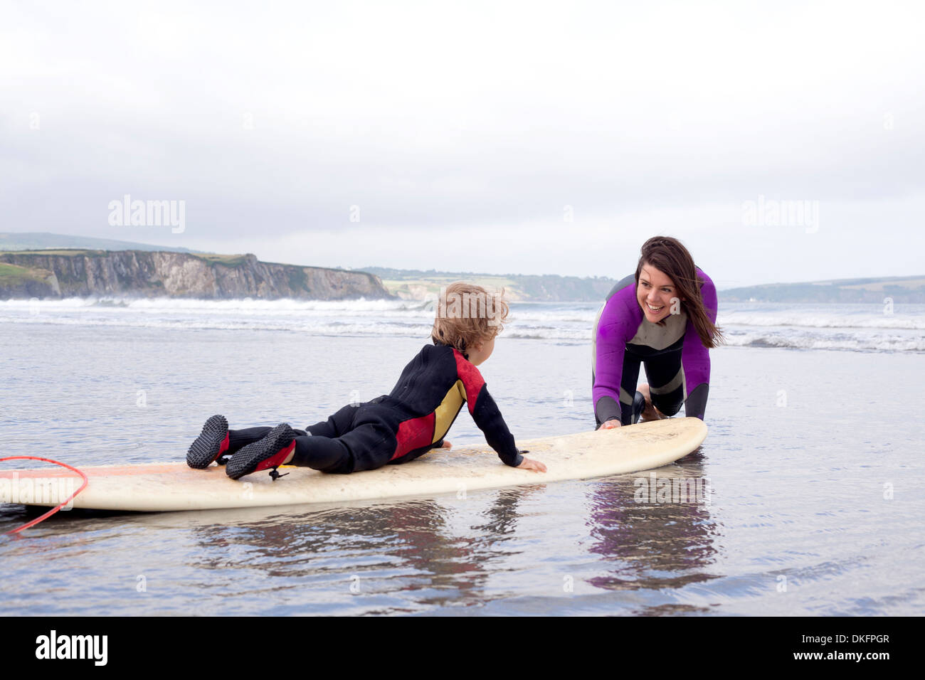 Mother teaching son how to surf Stock Photo