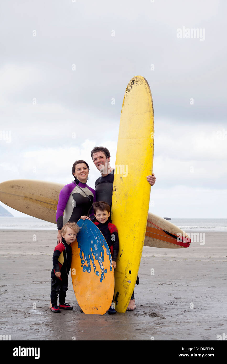 Portrait of family with two boys with surfboards on beach Stock Photo