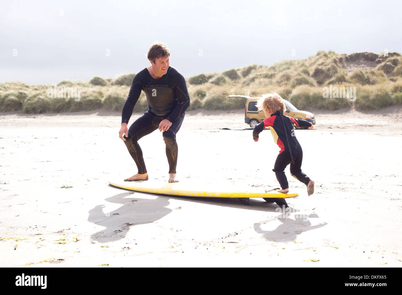 Father and son with surfboard on beach Stock Photo