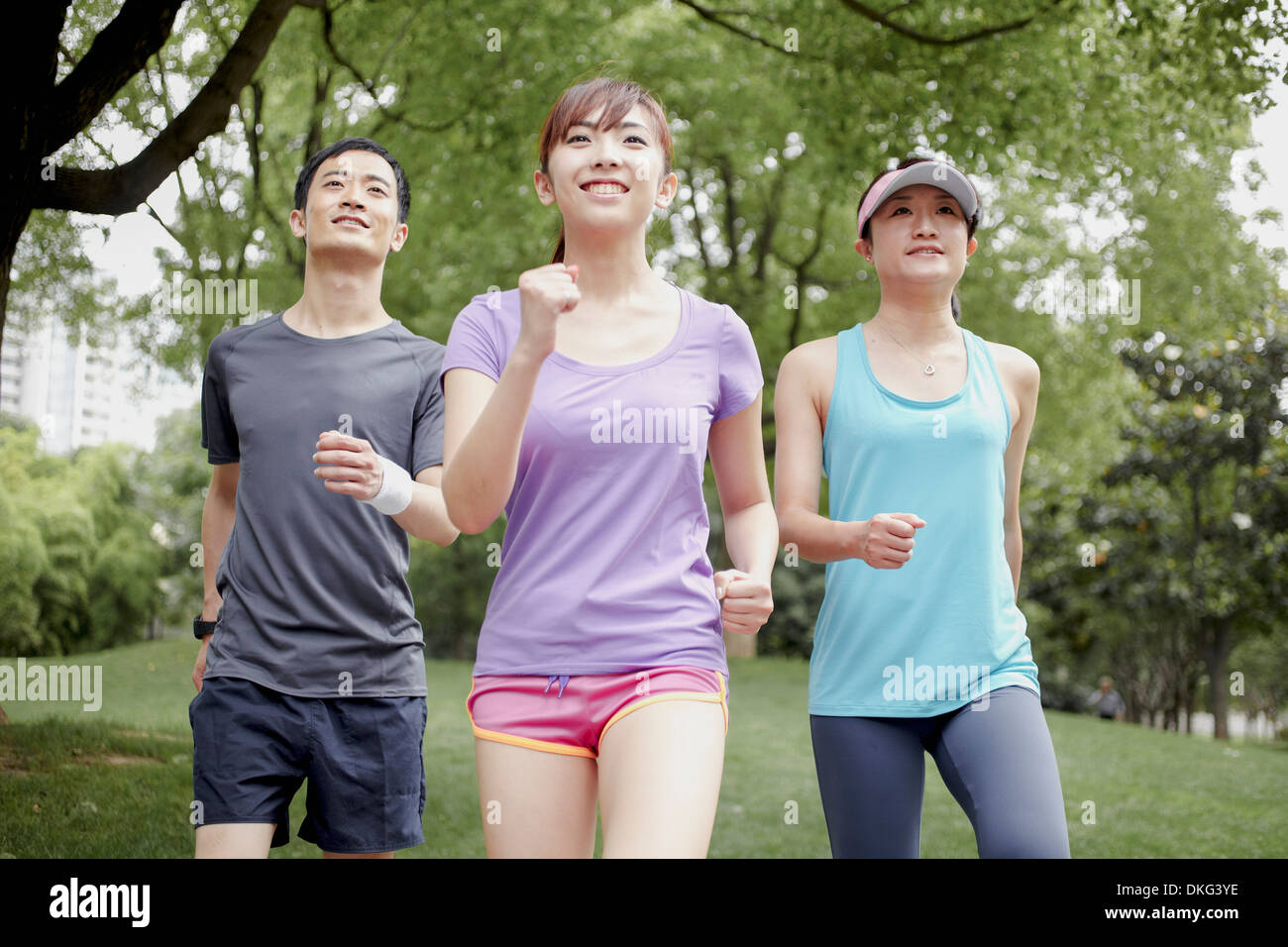 Three young people jogging in park Stock Photo