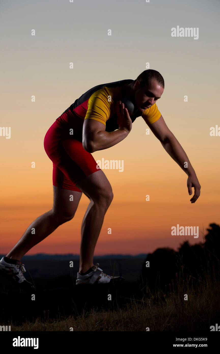Young man preparing to throw shot put at sunset Stock Photo Alamy