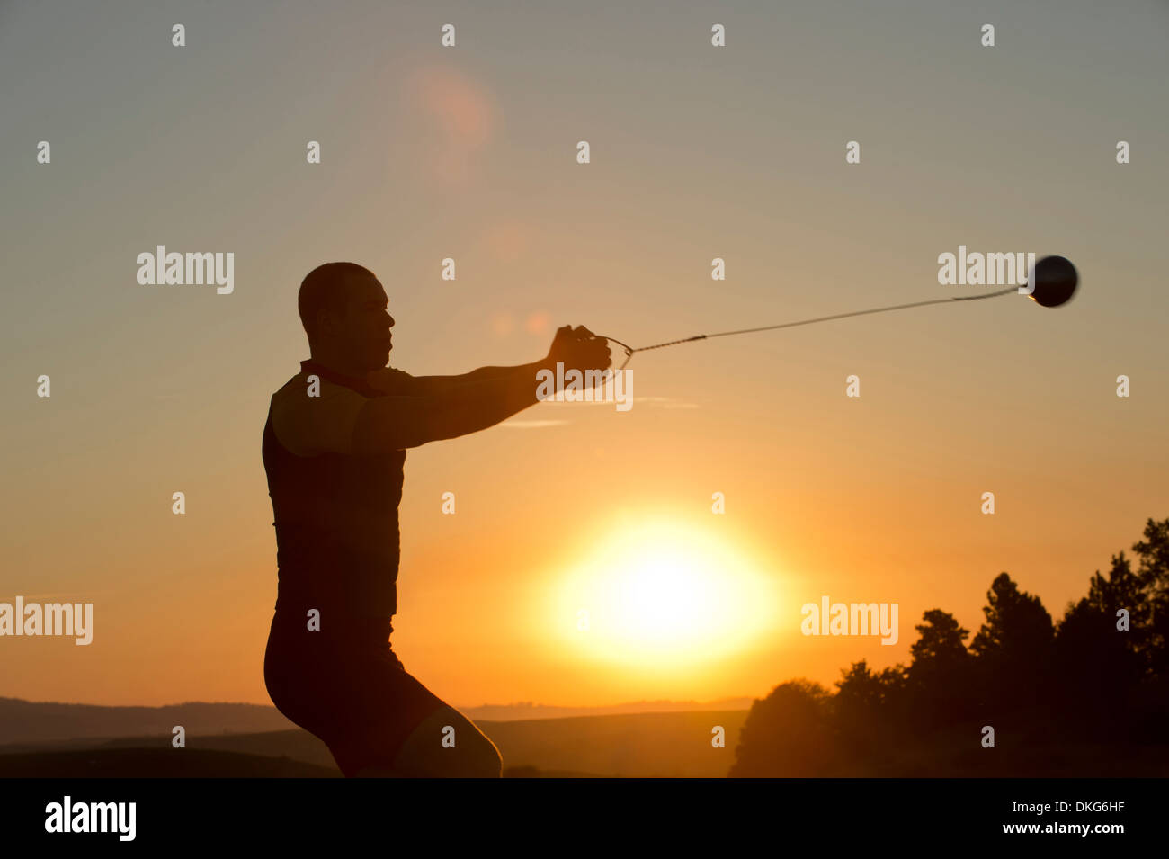 Young man preparing to throw the hammer at sunset Stock Photo