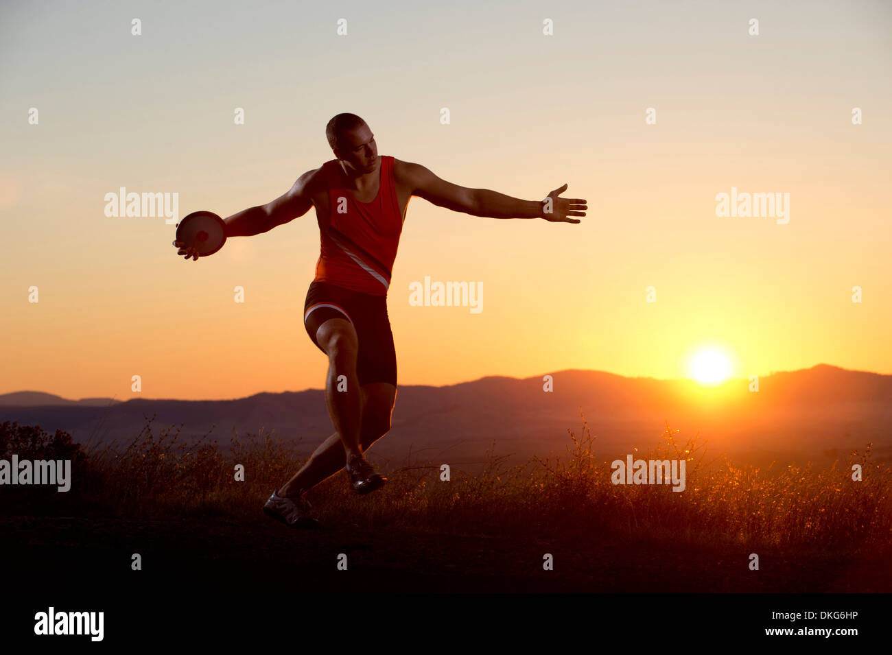 Young man preparing to throwing discus at sunset Stock Photo