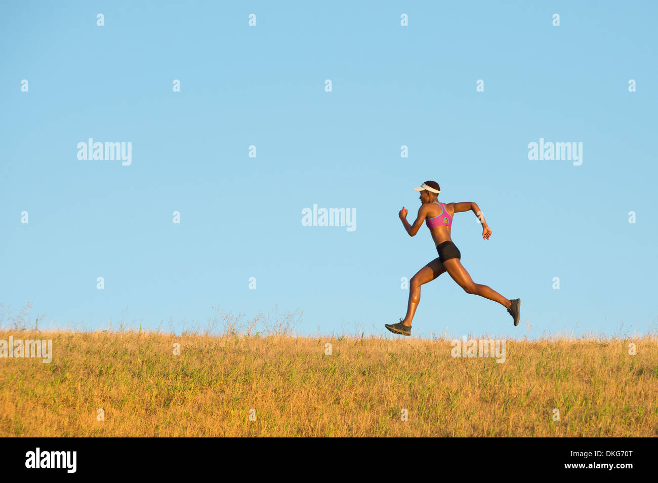 Young woman running across field Stock Photo