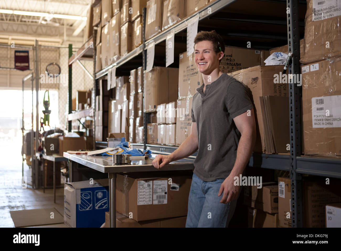 Worker standing in warehouse, leaning against shelving Stock Photo Alamy