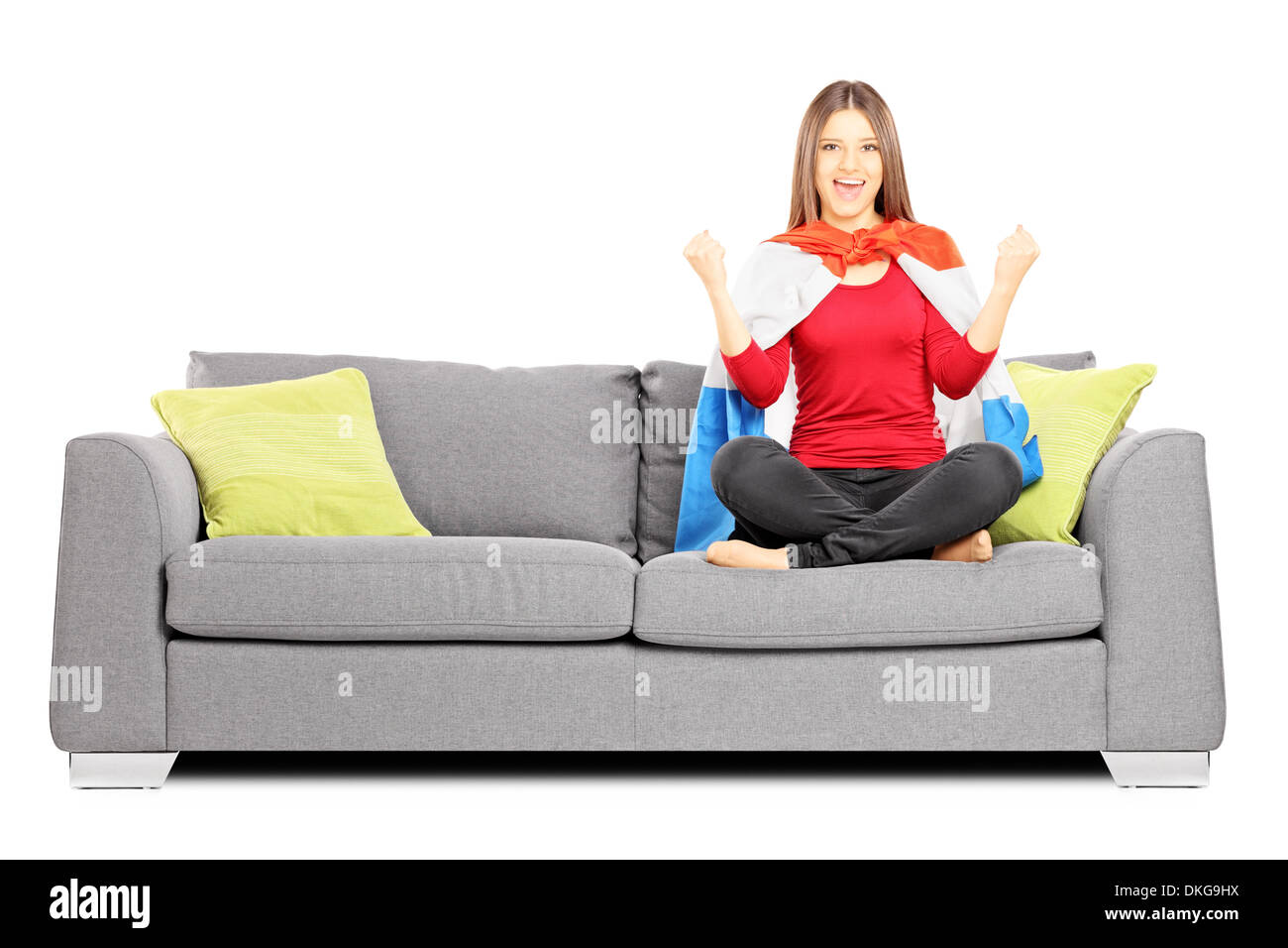 Young female sport supporter sitting on a modern sofa and cheering Stock Photo