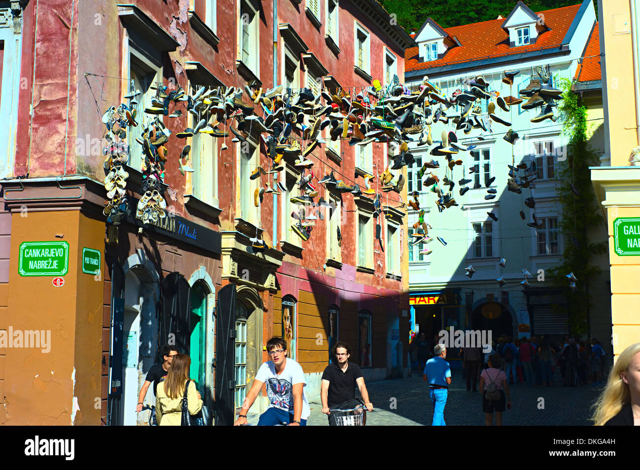 People are passing by famous place where shoes hanging on wire in the Old Town of Ljubljana. Stock Photo