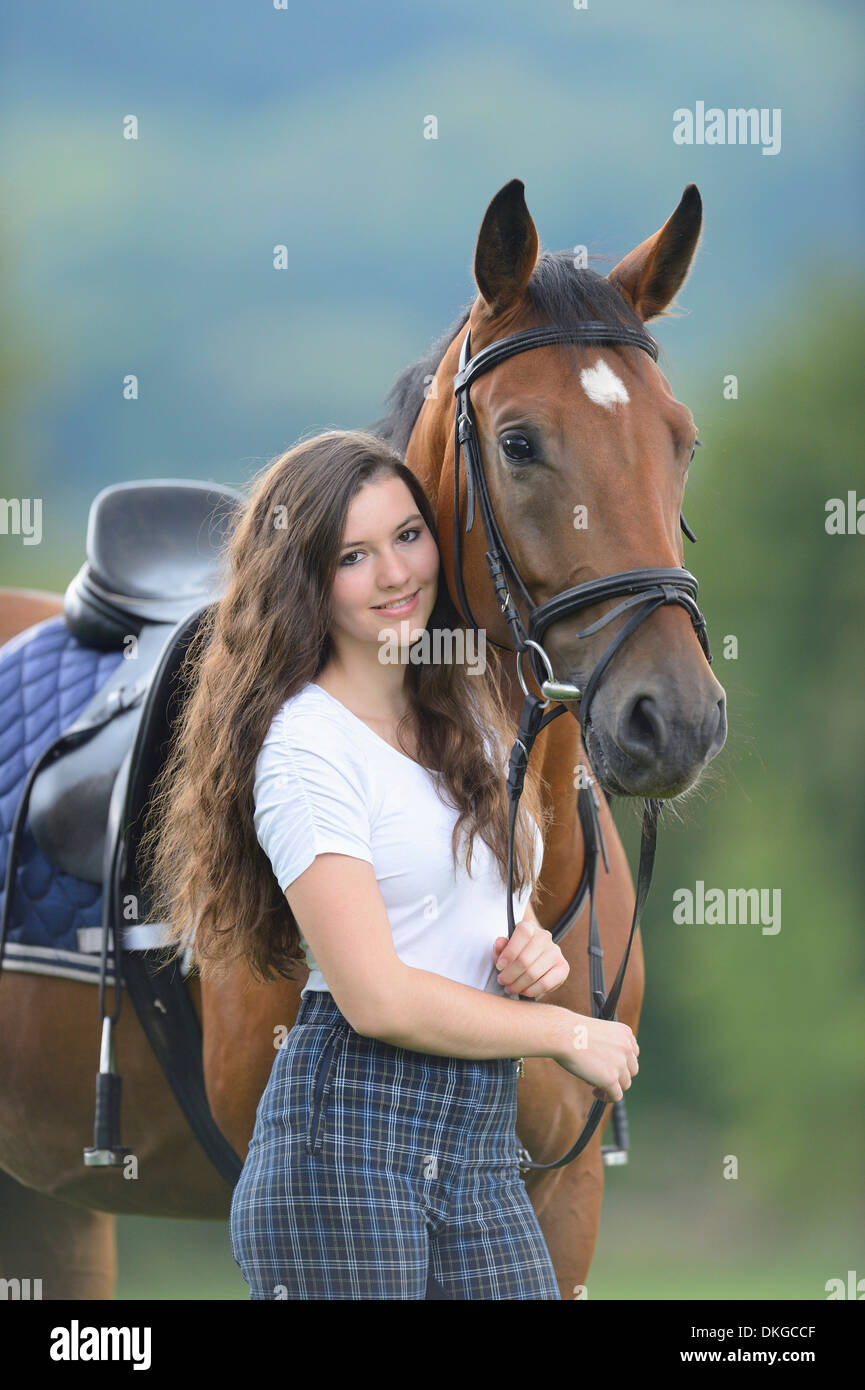 Teenage girl standing with a Mecklenburger horse on a paddock Stock Photo