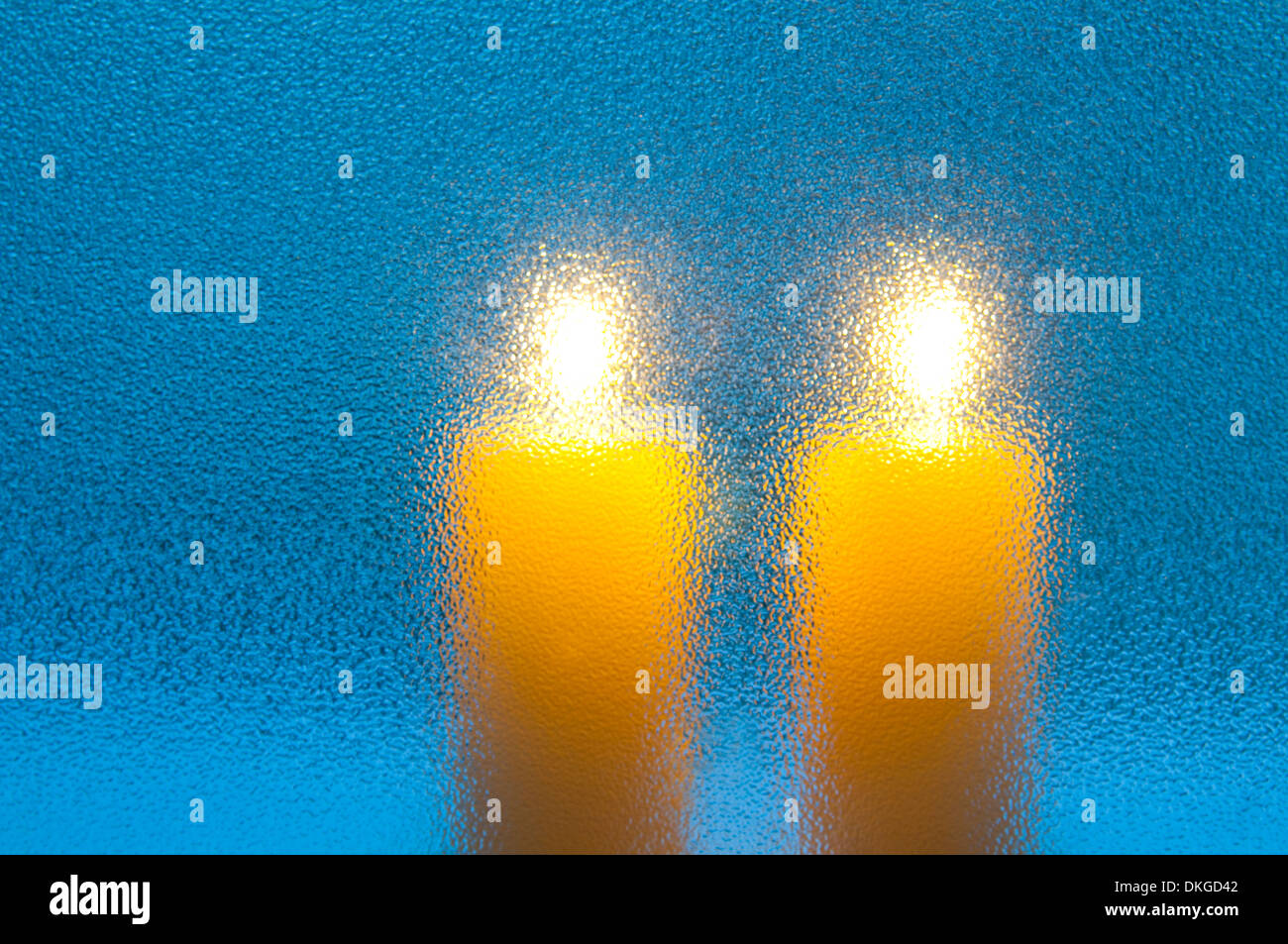 Two lit up candles viewed through a frosted glass. Stock Photo
