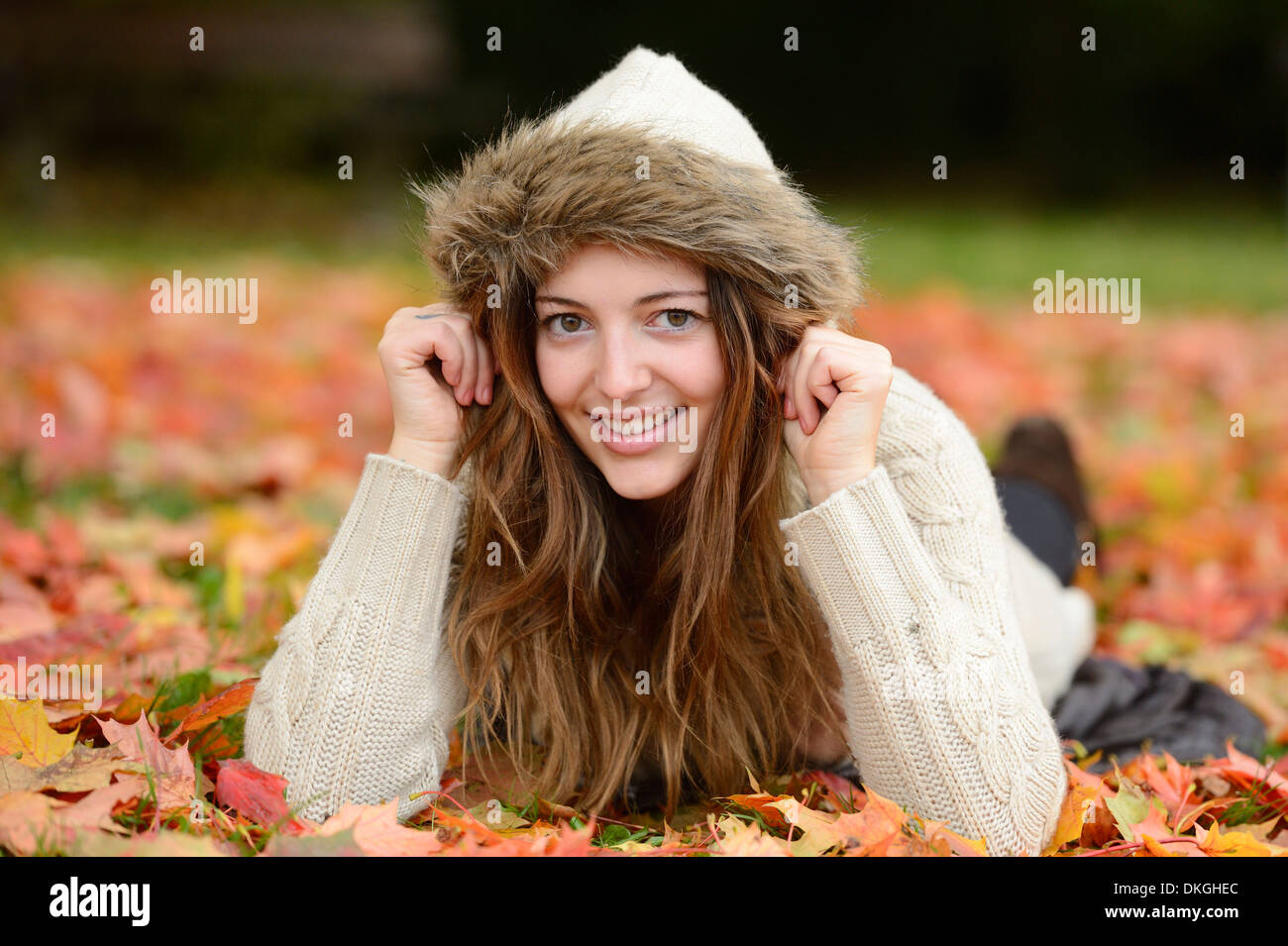 Smiling young woman lying in autumn leaves Stock Photo - Alamy