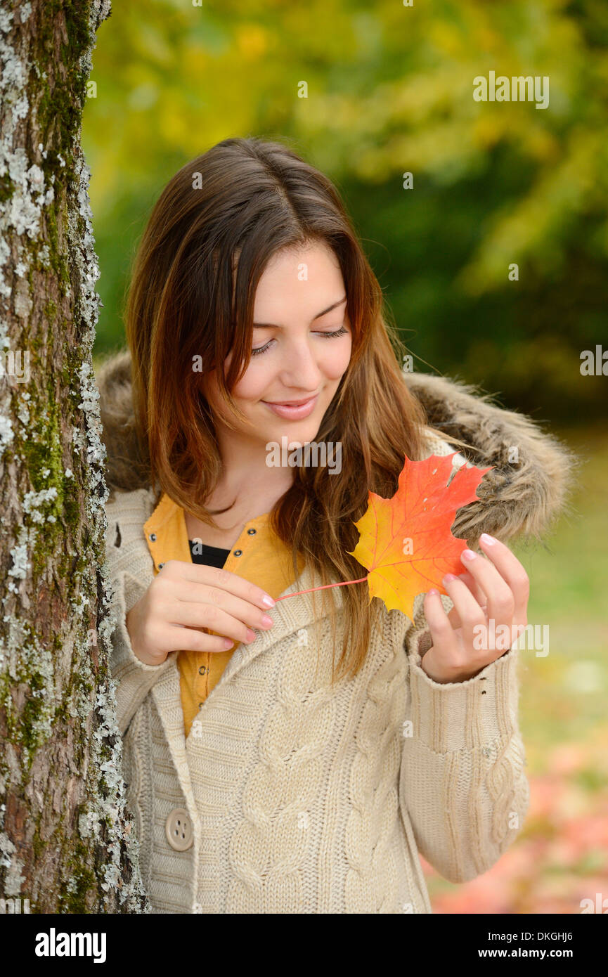 Smiling young woman holding autumn leaf Stock Photo