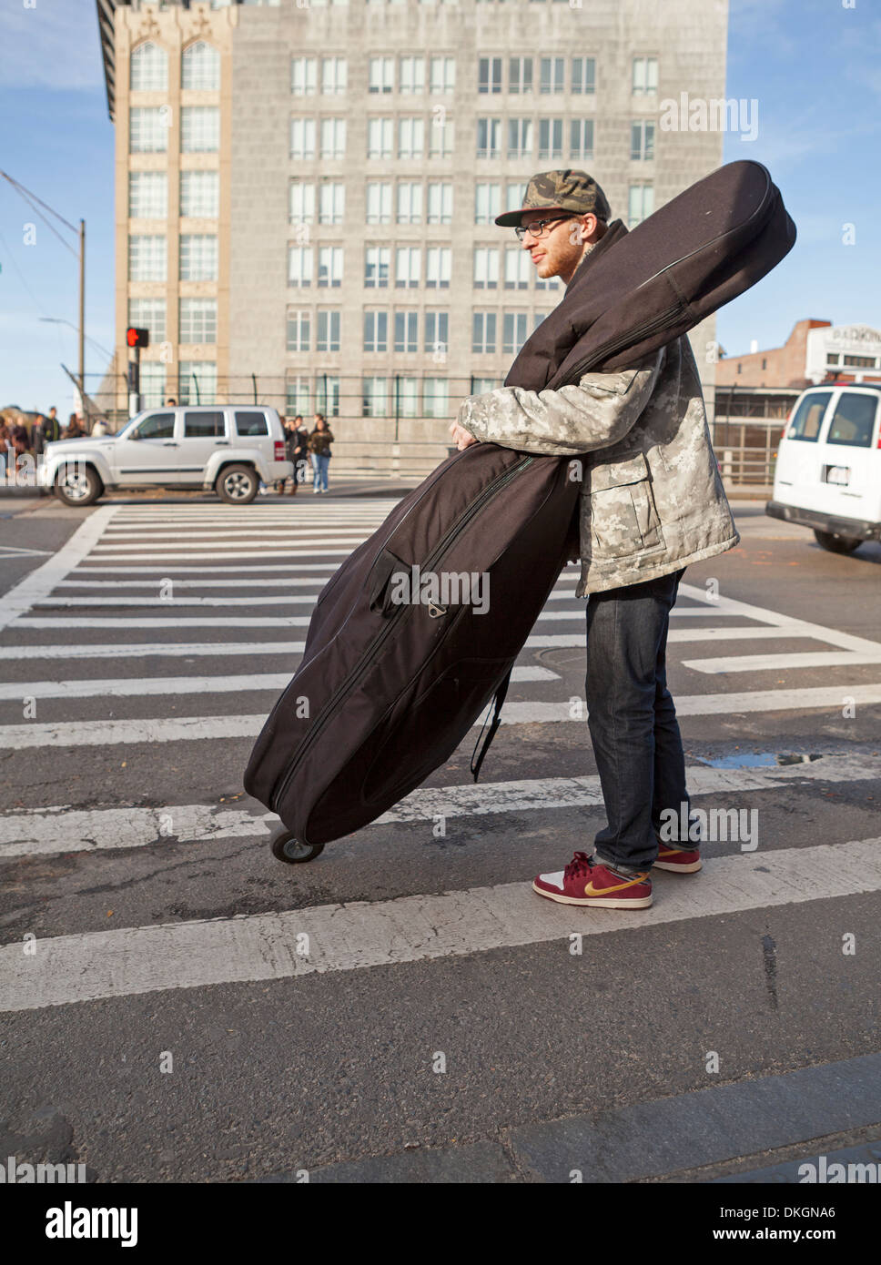 A student wheels his stand up bass across a street in Boston. Stock Photo