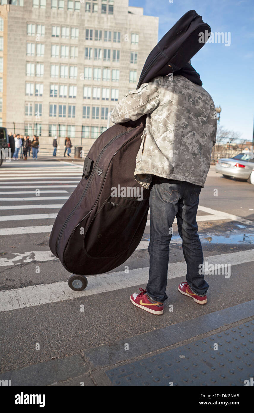 A student wheels his stand up bass across a street in Boston. Stock Photo