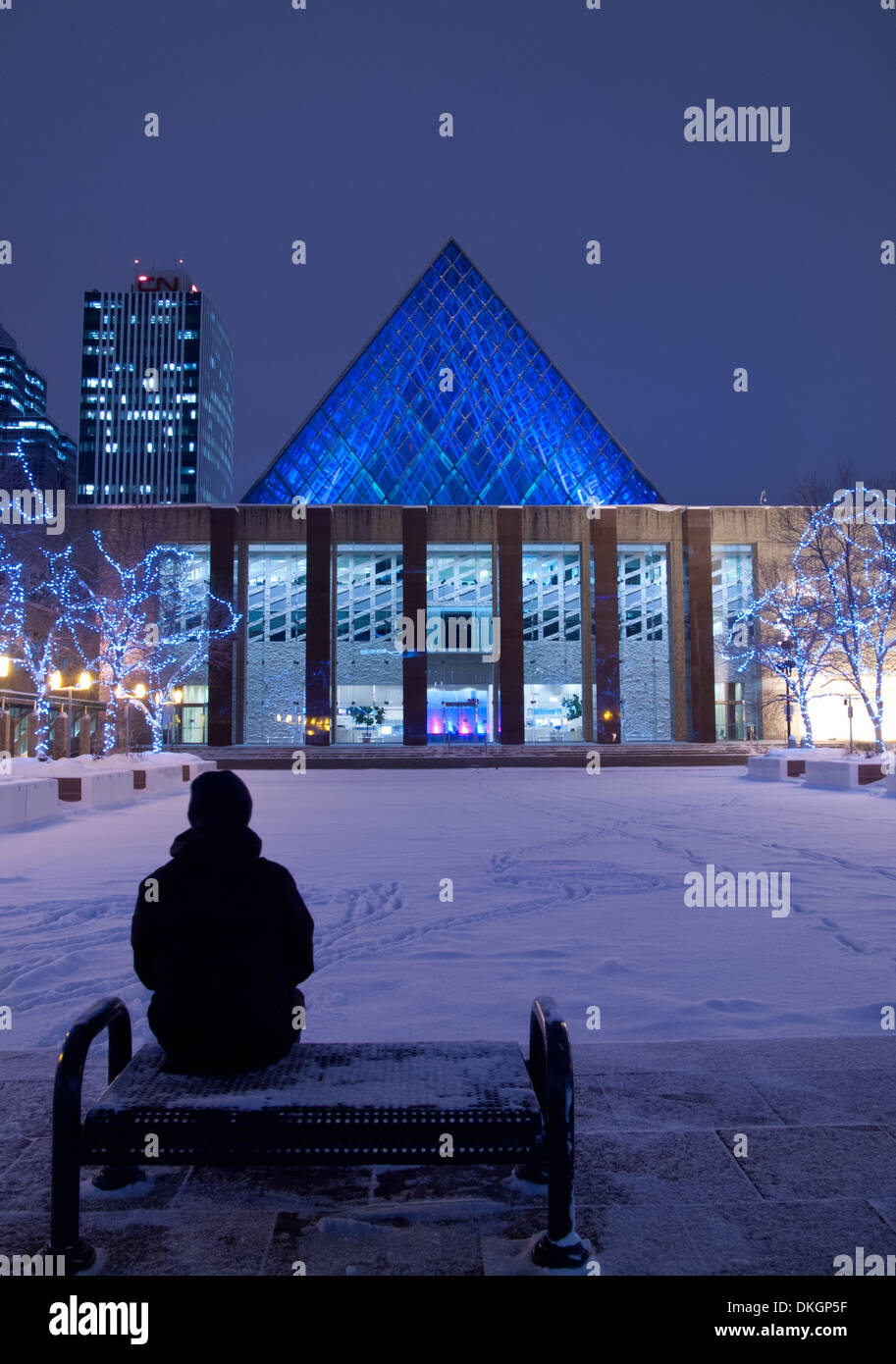 A man dressed in winter gear, sitting on a park bench at Edmonton City Hall in Edmonton, Alberta, Canada. Stock Photo