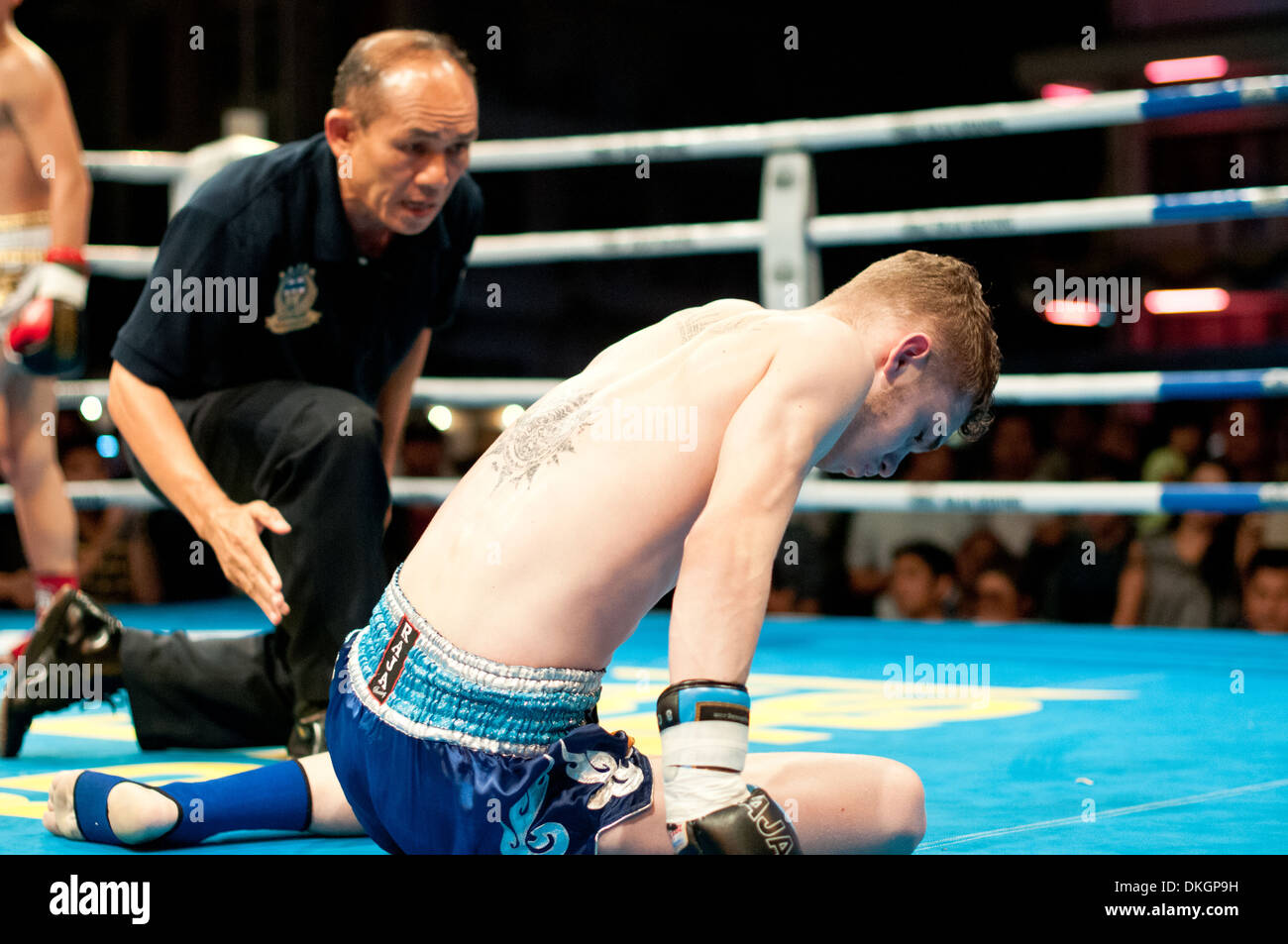 Thai boxer receives an eight count after being knocked down by his opponent Stock Photo