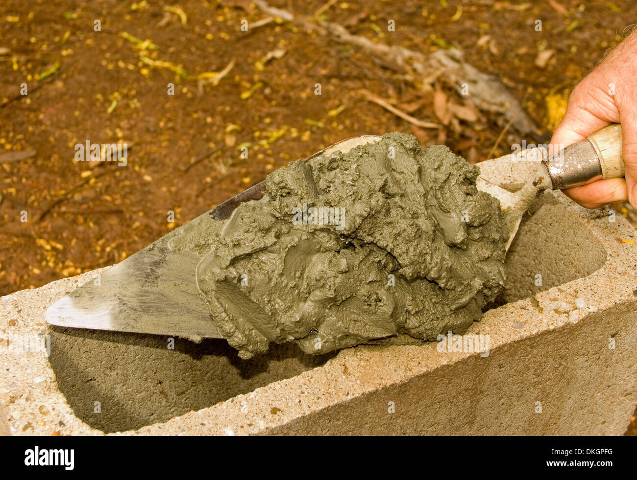 Hand holding pointed bricklayer's trowel with mortar ready to be laid
