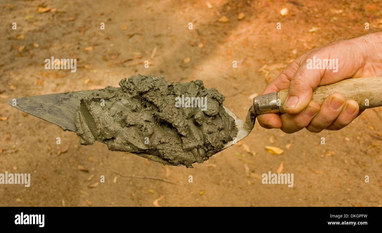 Hand holding pointed bricklayer's trowel with mortar ready to be laid