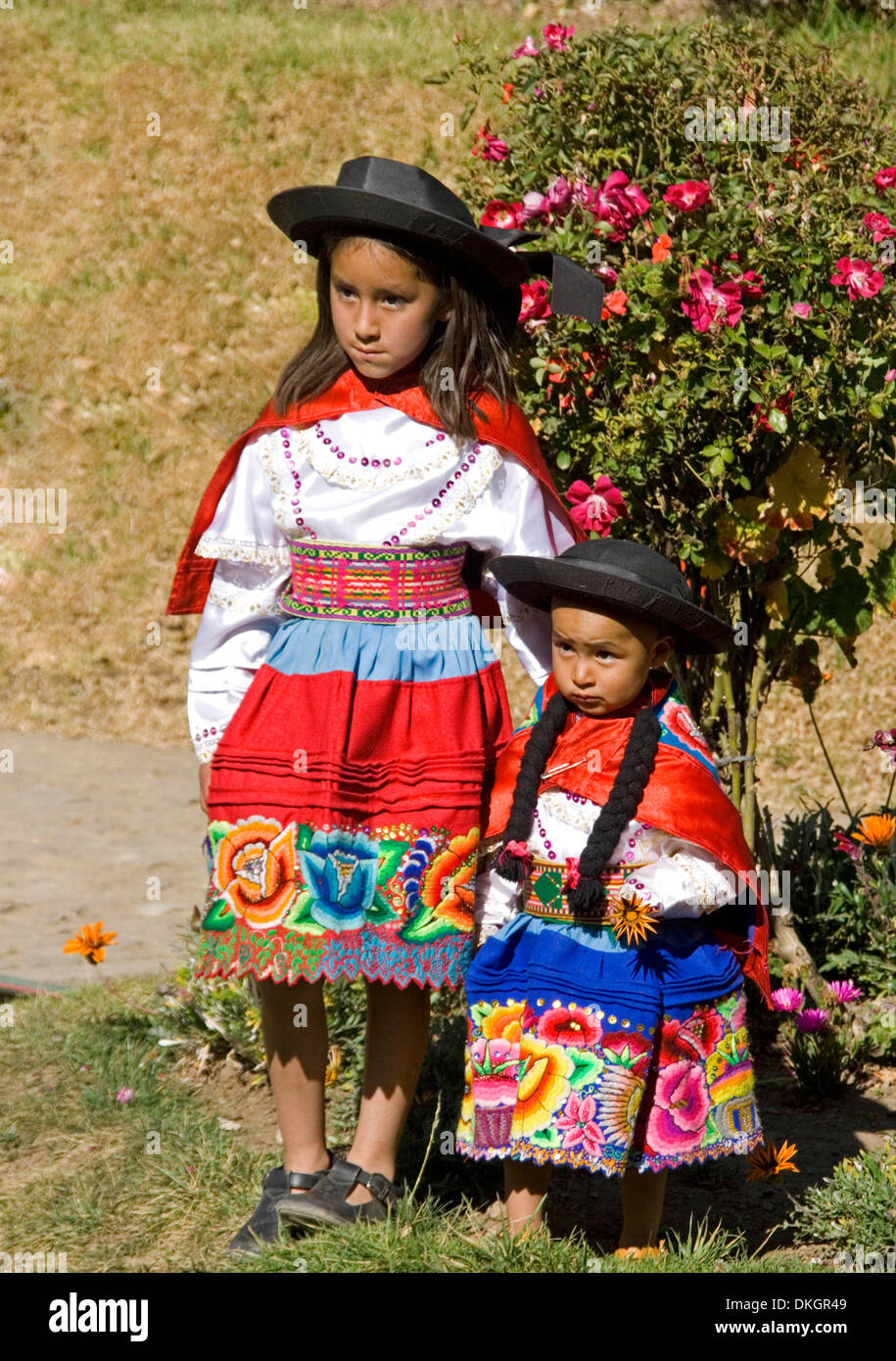 Two young Peruvian girls dressed in colourful traditional costume posing for a photo in village in Andes Mountains in Peru Stock Photo