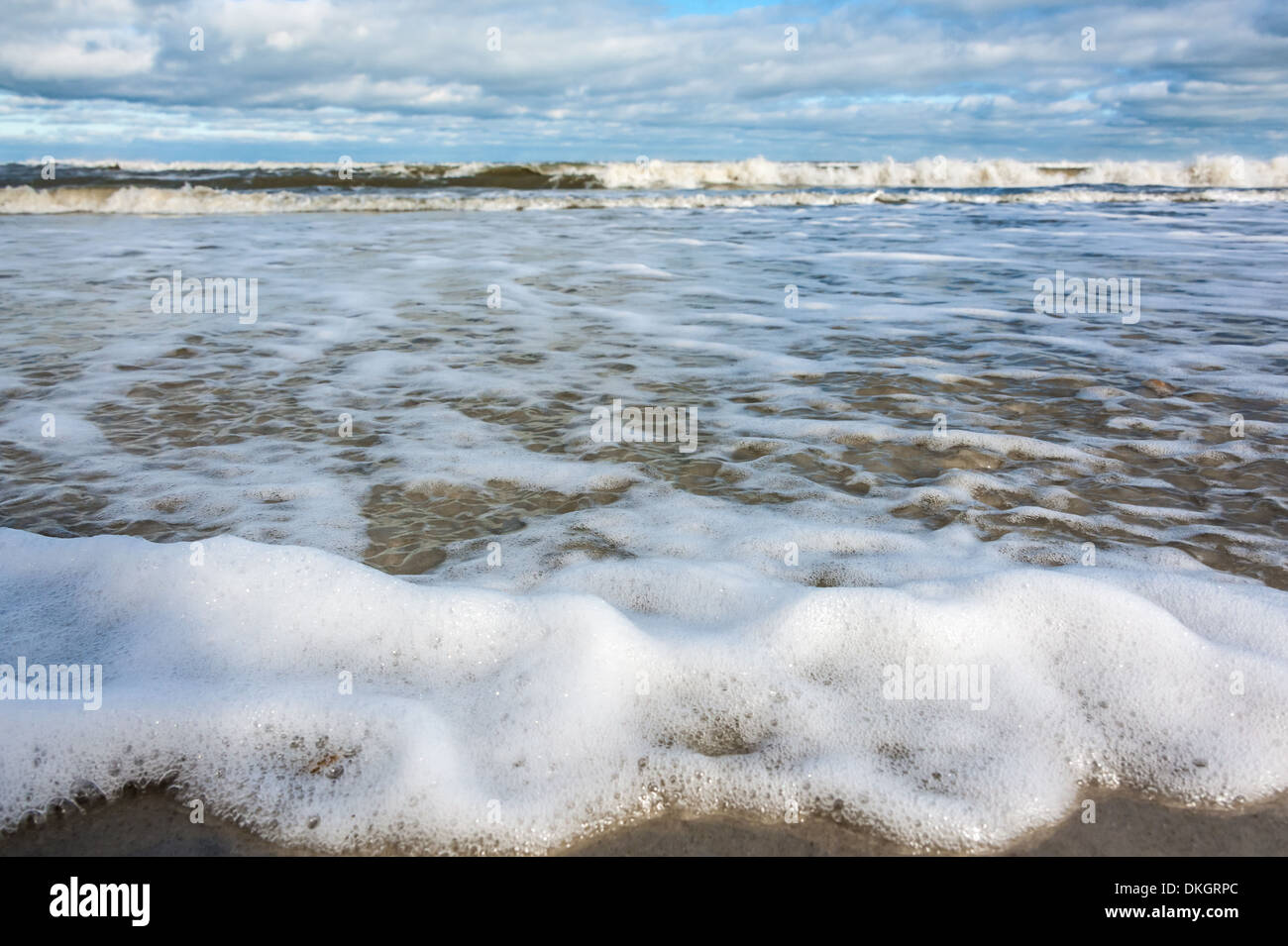 Ocean waves spread thin, foam-laced sheets of water across the sandy shoreline of Jacksonville Beach, Florida. (USA) Stock Photo