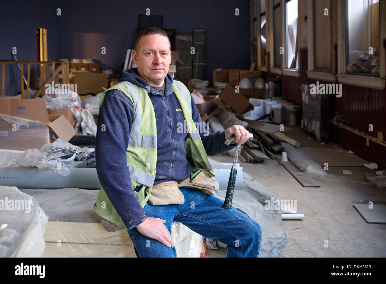John Shaw, joiner, sitting in a ground floor room used for storage, Fairfield, Govan, Glasgow Stock Photo