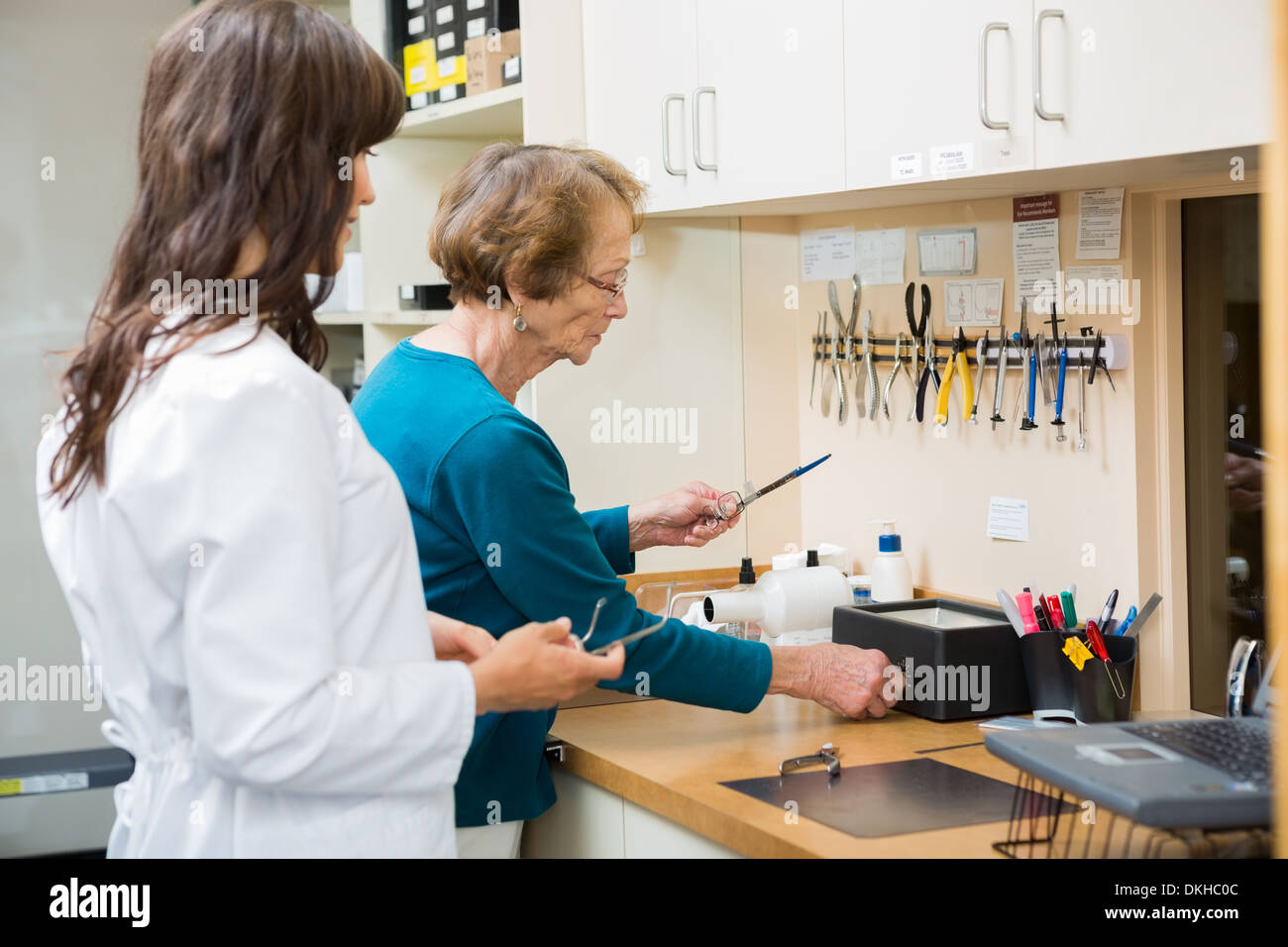 Optician With Apprentice Repairing Glasses In Workshop Stock Photo