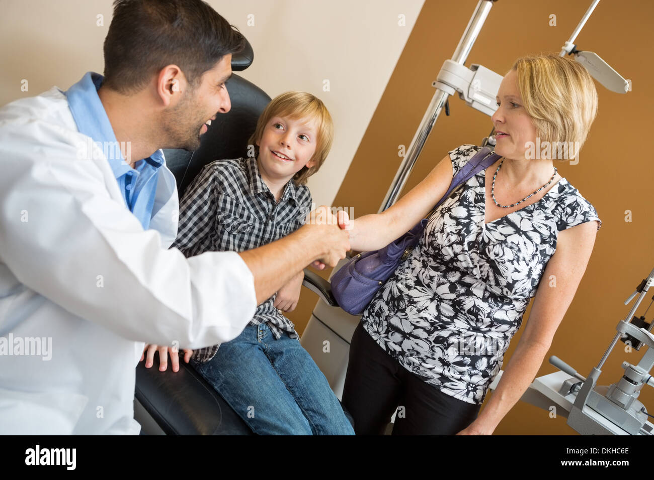 Optician And Woman Shaking Hands By Boy Stock Photo