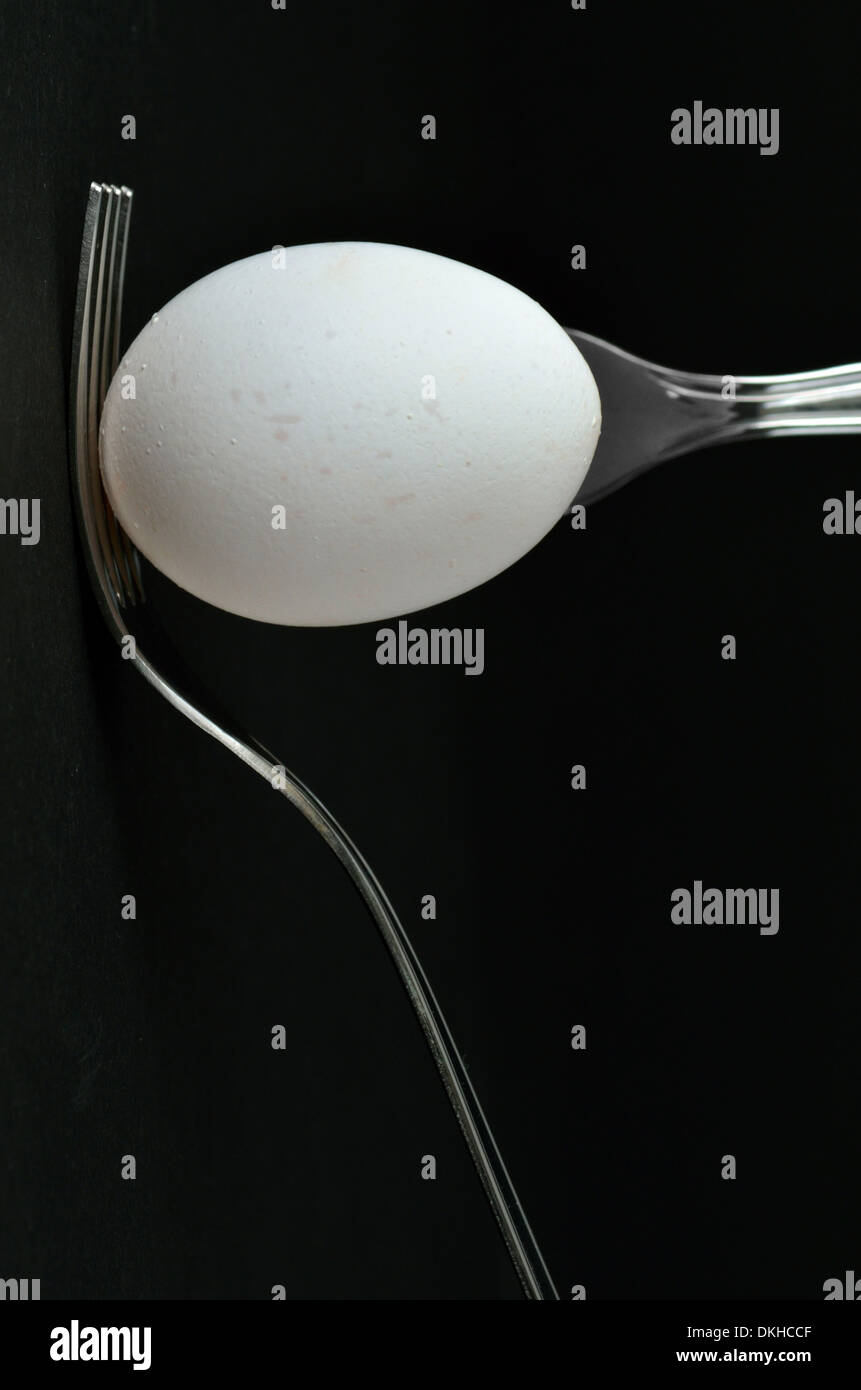 an egg and two forks on black background Stock Photo