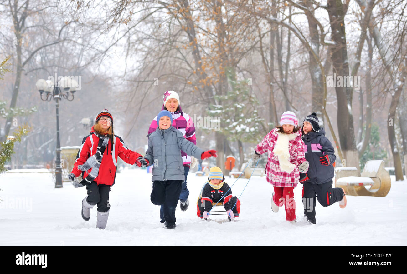 group of children and adult playing on snow in winter time, young girl ...