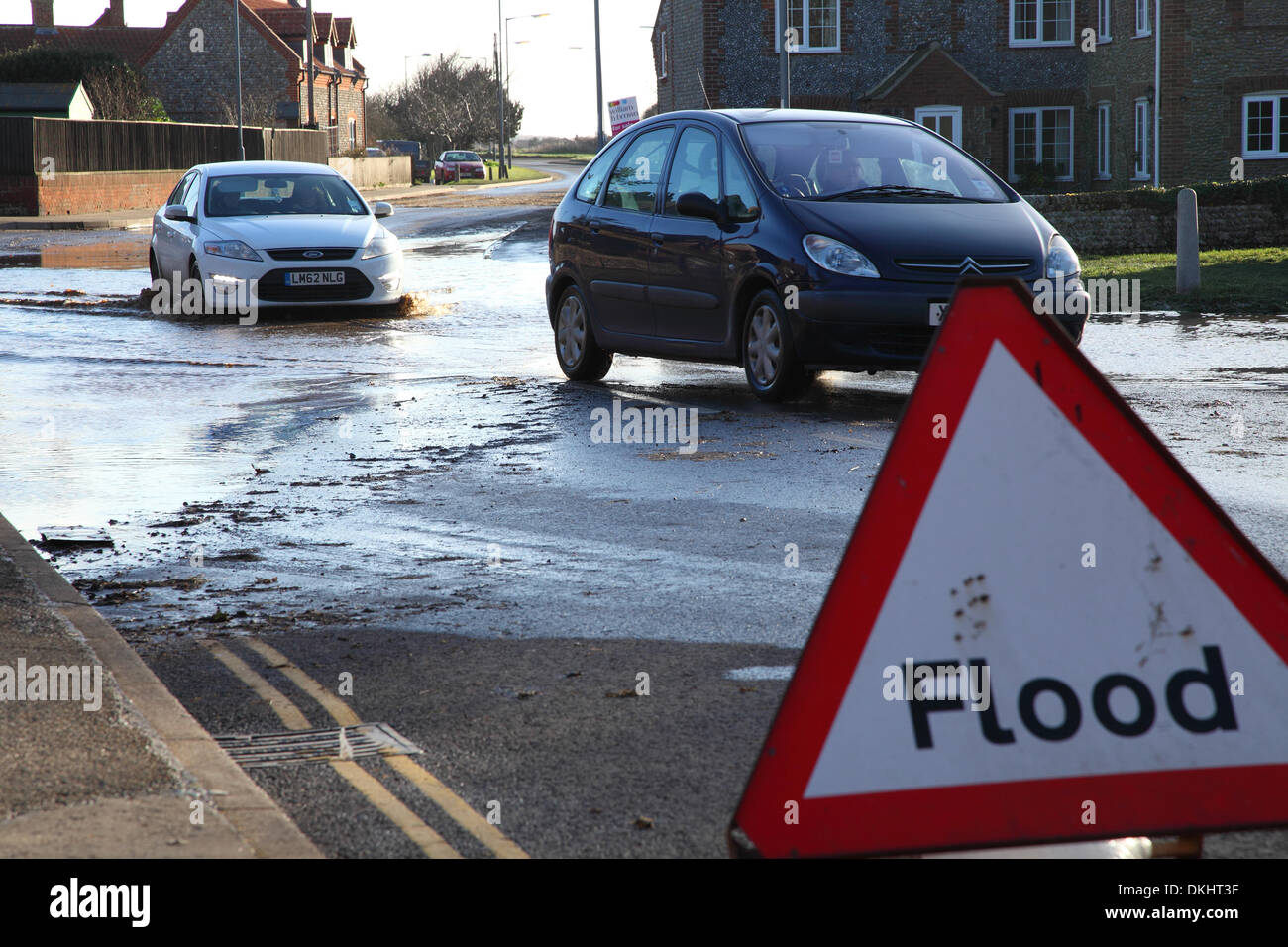 Heavy rain and storms hit the UK, Cars are seen here driving through flood water past a flood warning sign. Stock Photo